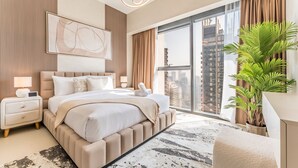 A modern hotel bedroom with a large bed, a nightstand, a potted plant, and a city view.