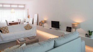En moderne stue med sofa, sofabord, fjernsyn og dekorativ belysning.