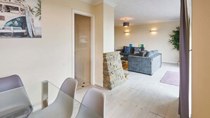 Una sala de estar moderna con chimenea de piedra, un sofá gris y una mesa de comedor de cristal con sillas.