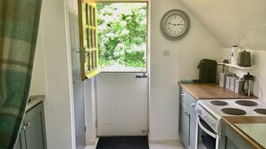 A compact kitchen with a window, a clock, and basic appliances.