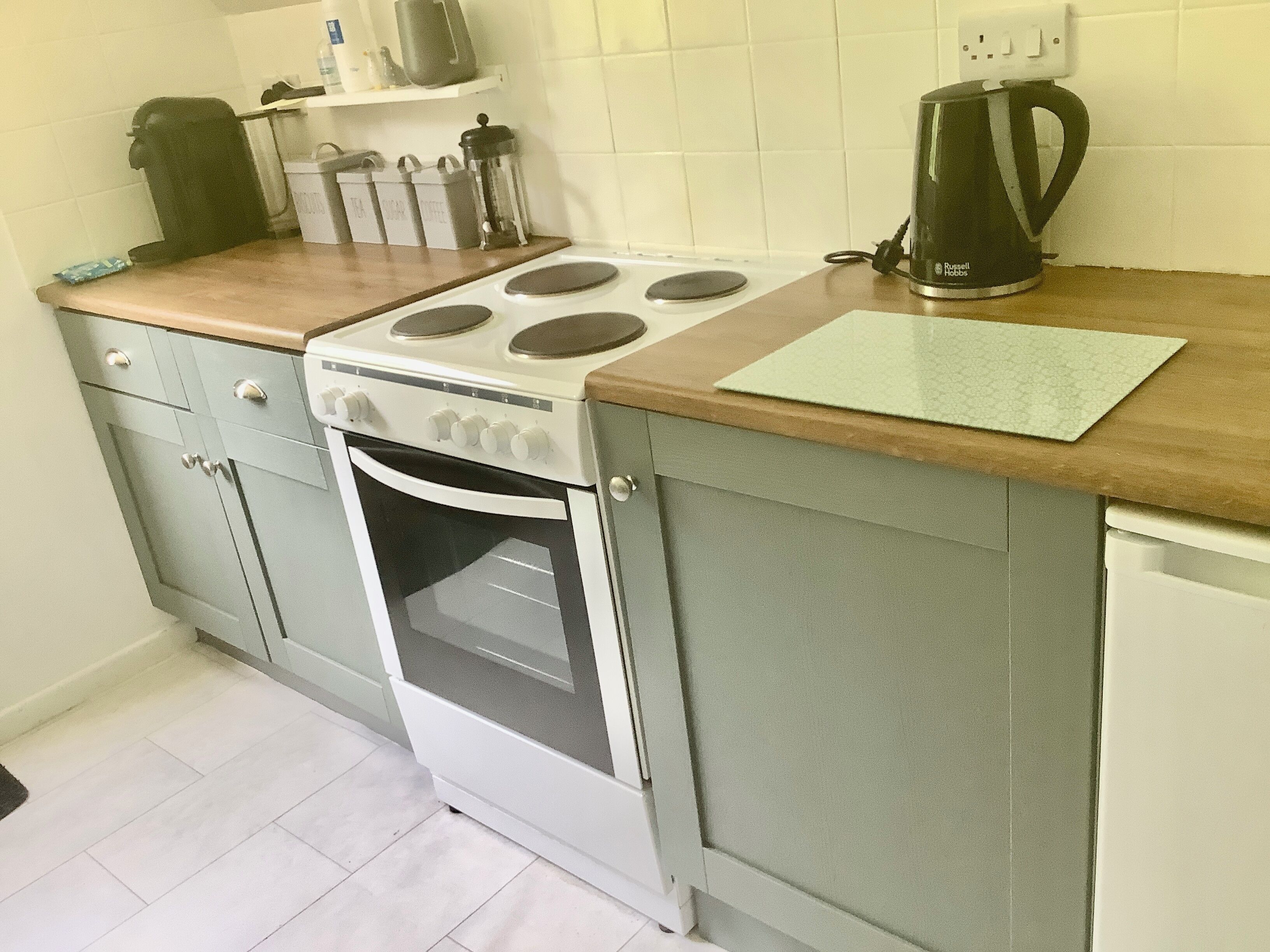 A kitchen with a white stove, a coffee maker, and storage containers on the counter.