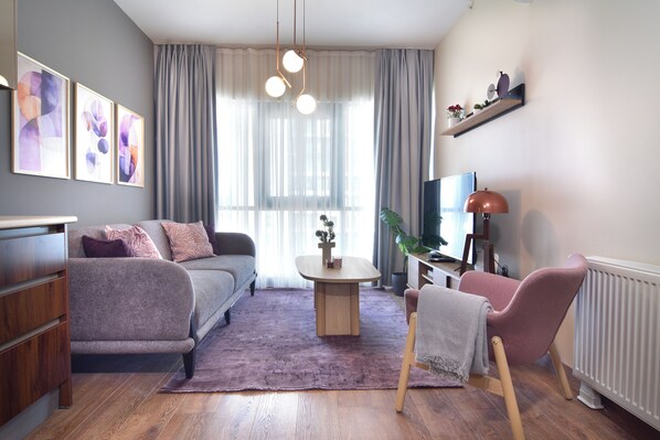 Ein modernes Wohnzimmer mit einer Couch, einem Couchtisch, einem Sessel und einem Fernseher.