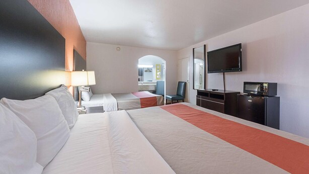 A hotel room with a large bed, a desk with a chair, a television, a microwave, and a small kitchenette. - Motel6 San Antonio, TX - I-10 West (San Antonio)