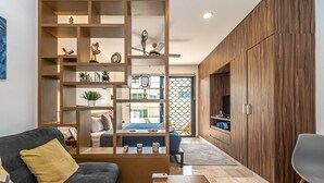 A modern living room with a built-in wooden shelving unit, a sofa, a coffee table, and a TV cabinet. - Ocean View Apt 2 blocks away from beach (Playa del Carmen)