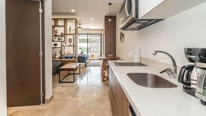 A modern kitchen with a built-in oven, a coffee maker, and a sink. - Ocean View Apt 2 blocks away from beach (Playa del Carmen)