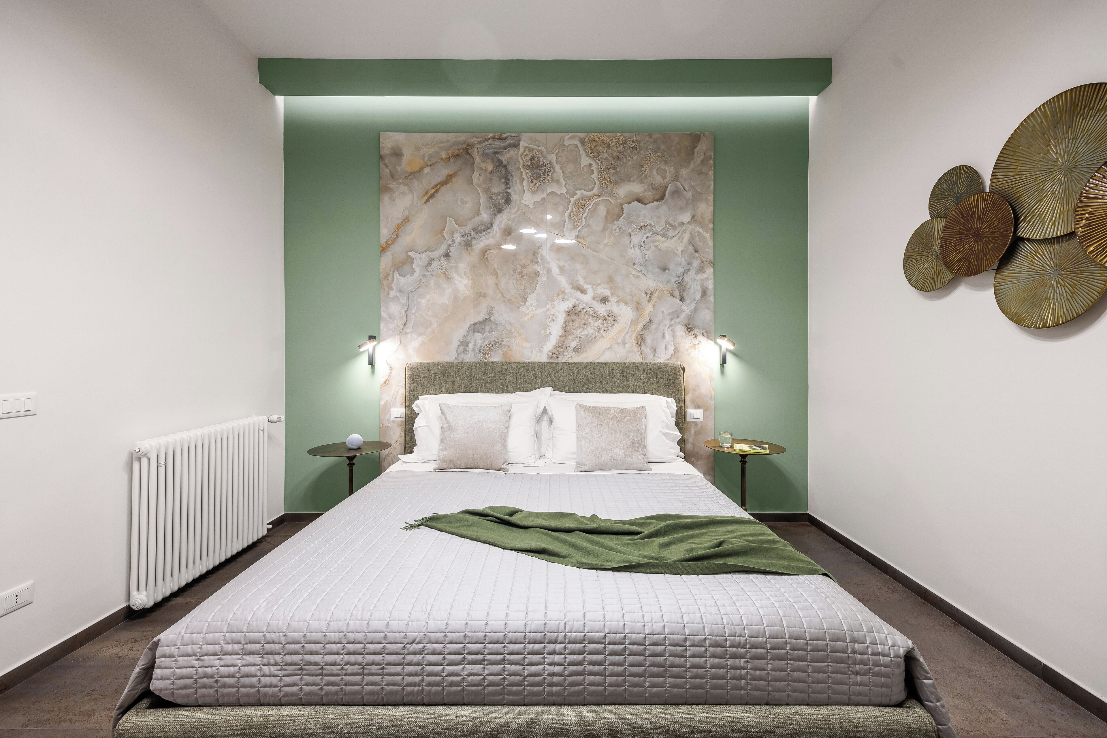 A modern bedroom with a large bed, a marble wall, and a decorative wall piece.