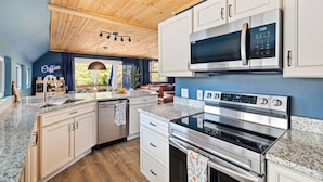 Una cucina moderna con piani in granito, elettrodomestici in acciaio inossidabile e soffitto in legno.