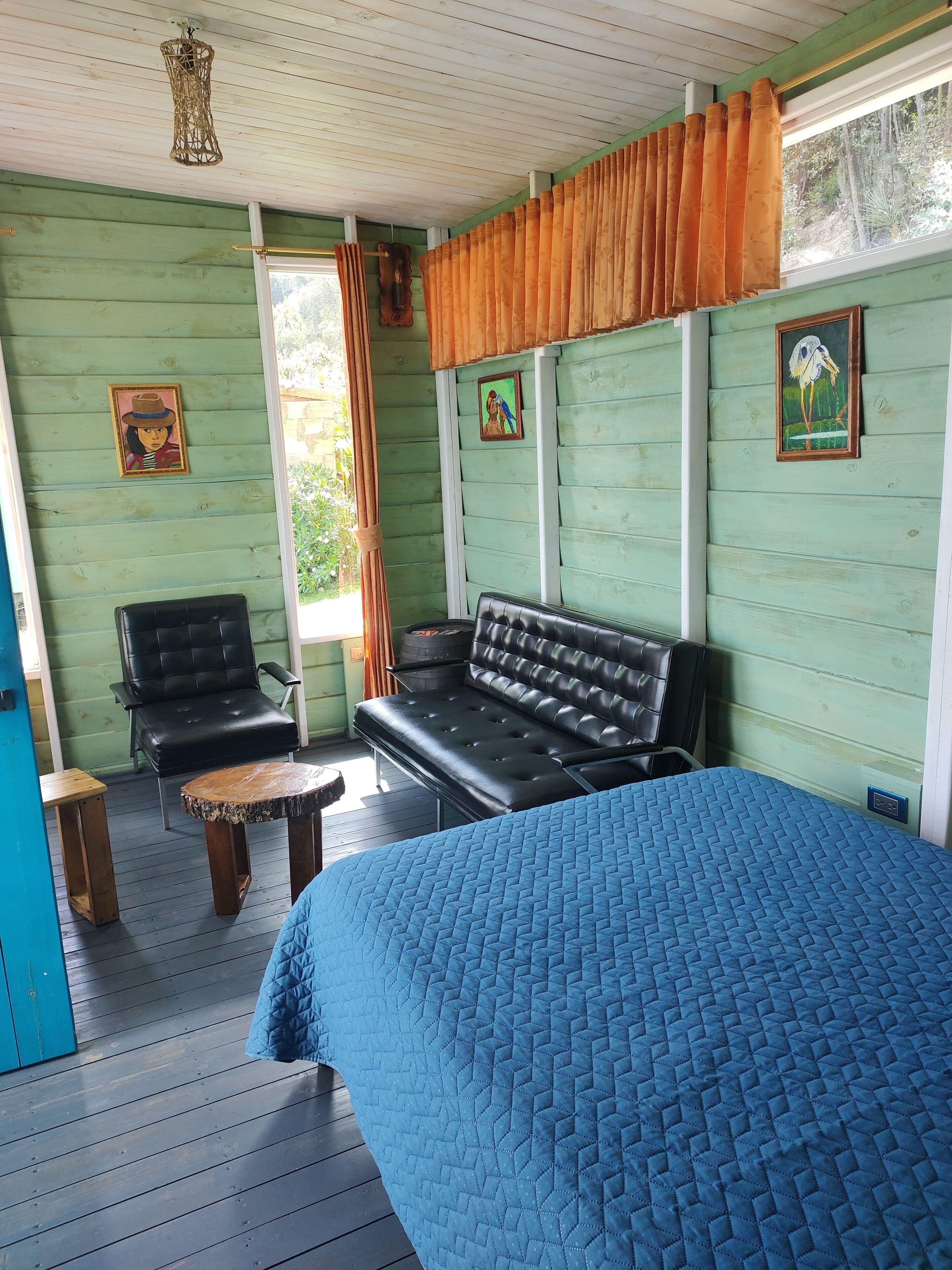 Une pièce comprenant un lit, un canapé en cuir noir, une table en bois et une chaise.