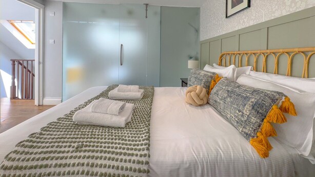 A modern bedroom with a large bed, a wardrobe, and a headboard with a unique design. - Pass the Keys | Central 2 Bed 2 Bath Duplex (London)