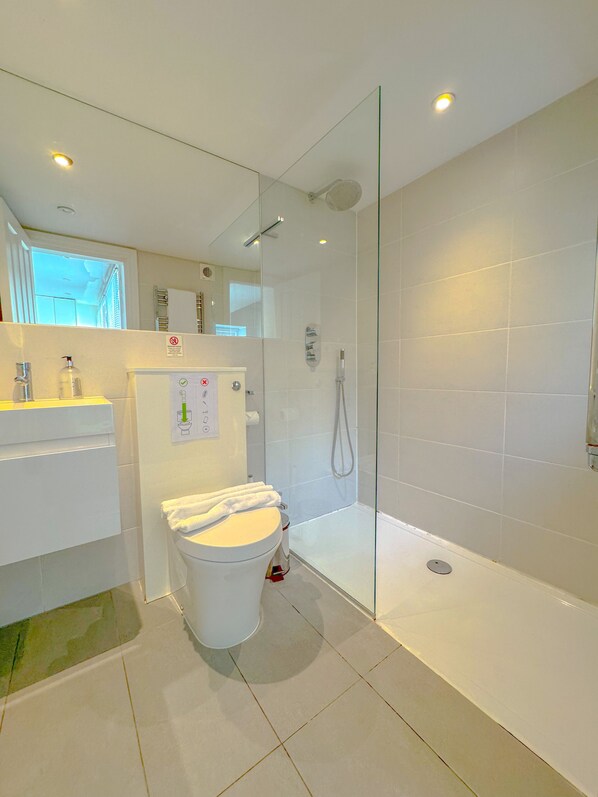 A modern bathroom with a glass-enclosed shower, a white toilet, and a sink with a mirror above it.