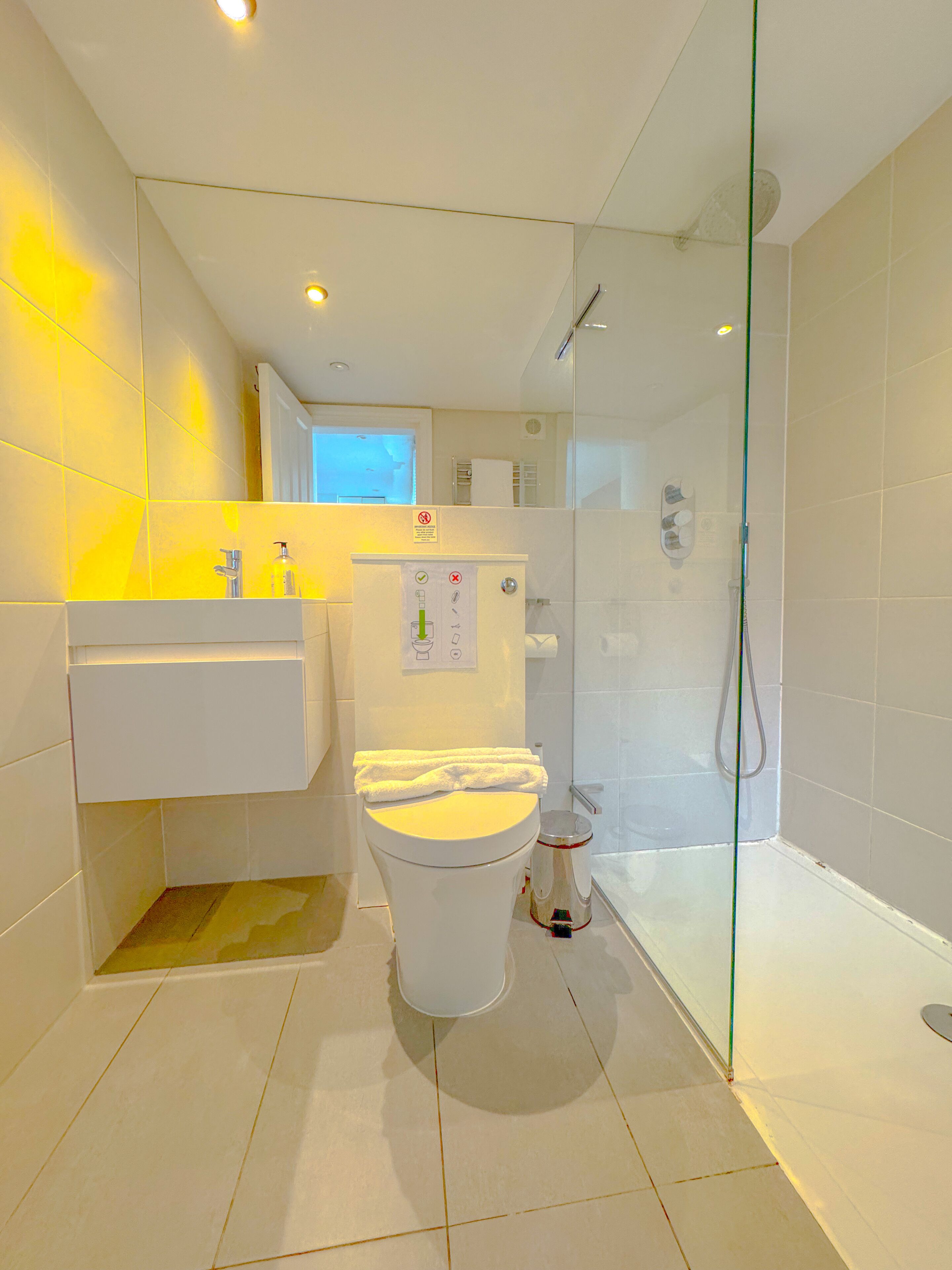 Een moderne badkamer met een douchecabine van glas, een toilet en een wastafel met spiegel.