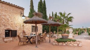 An outdoor patio with stone walls, wicker furniture, and thatched umbrellas. - Banc Doli - Villa With Private Pool In Manacor (Manacor, Illes Balears)