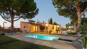 A poolside area with a swimming pool, lounge chairs, and a stone building with a tiled roof. - Banc Doli - Villa With Private Pool In Manacor (Manacor, Illes Balears)
