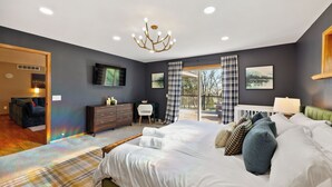 A bedroom with a large bed, a dresser, a chair, and a television on the wall. - Wild Timber Lodge: Golf Sim, Sauna, Bars, 10 acres, close to WI Dells (Oxford)
