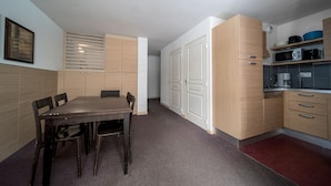 Une cuisine de taille réduite avec des meubles en bois, une table à manger avec des chaises et un four à micro-ondes.