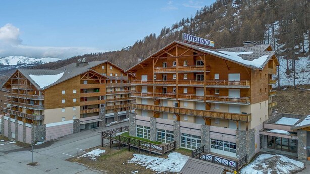 Un hôtel à plusieurs étages, doté d’une façade en bois, de balcons et d’une enseigne indiquant qu’il s’agit d’un hôtel.