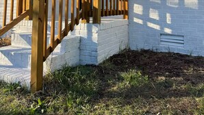 Une maison blanche d’un seul étage, dotée d’un porche en bois à l’avant et d’une petite fenêtre.