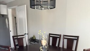 Une salle à manger avec une table en bois foncé, six chaises et un lustre.
