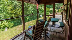 A wooden deck with a bench and table, overlooking a lush green landscape.