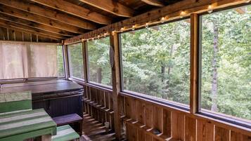A wooden deck with a bench and a table, overlooking a forested area.