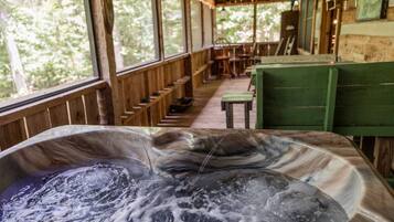 A hot tub with a wooden deck and large windows.
