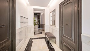 A hallway with marble flooring, a bench, lockers, and a door.