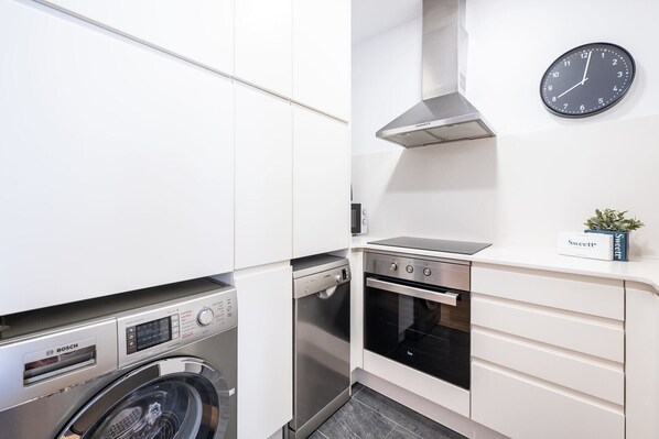 Cocina compacta con lavadora Bosch, horno y un reloj en la pared.