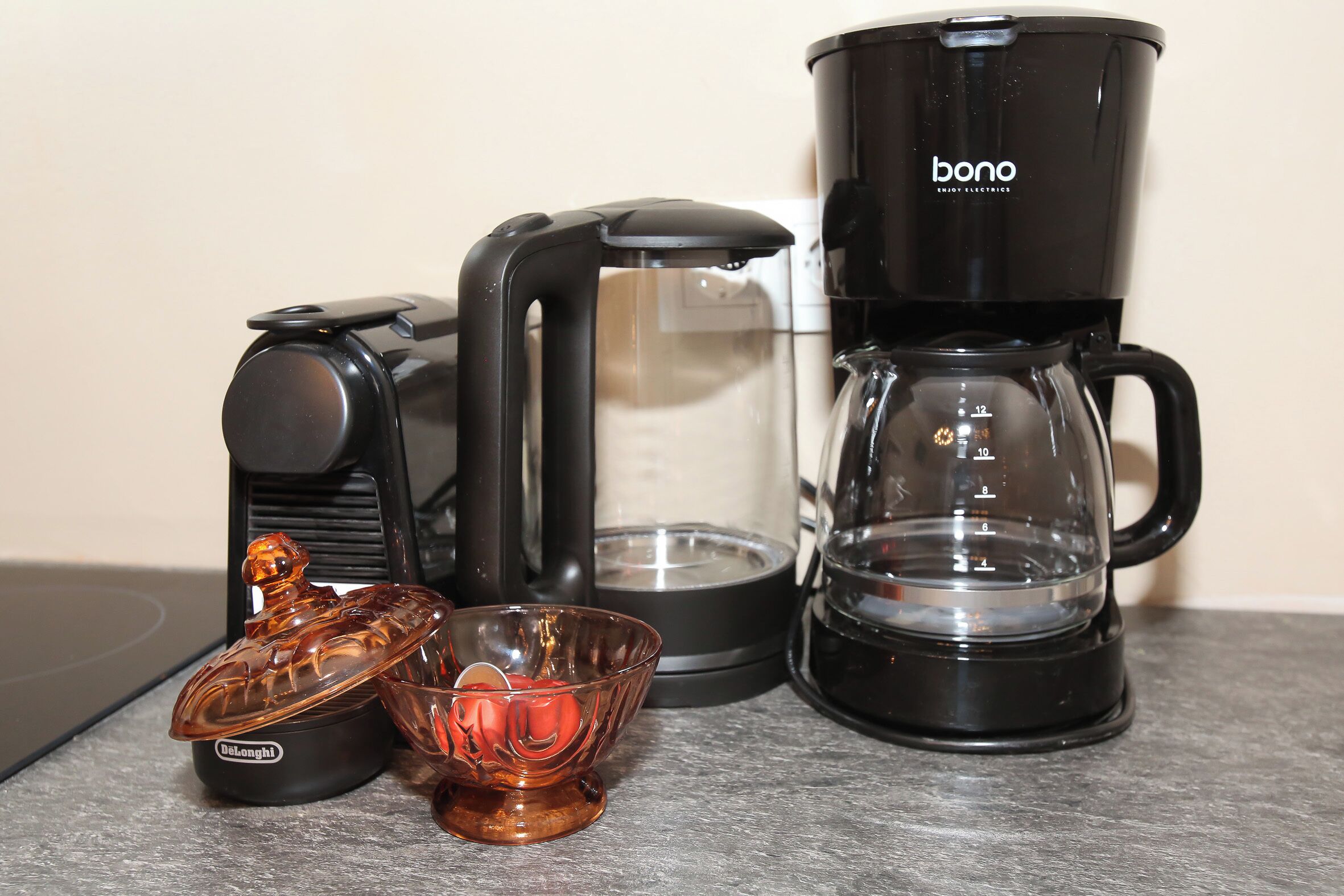 A black coffee maker, a glass carafe, and a glass coffee pot on a countertop.