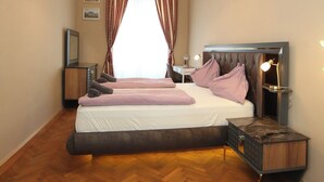 A bedroom with a large bed, a bedside table, a nightstand, a round rug, and a hanging light fixture.