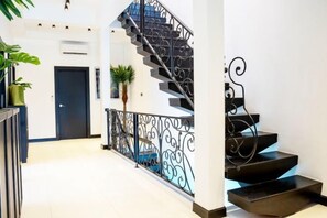 A staircase with ornate metal railings, a door at the bottom, and a potted plant to the left. - Art Pool Villa (Pattaya)