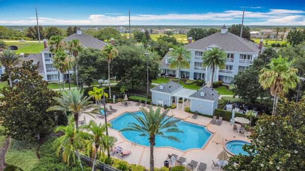 A resort with a central pool, multiple buildings, and lush greenery. - Disney Cozy 3BR Condo with Balcony, Walk to Pool (Kissimmee)