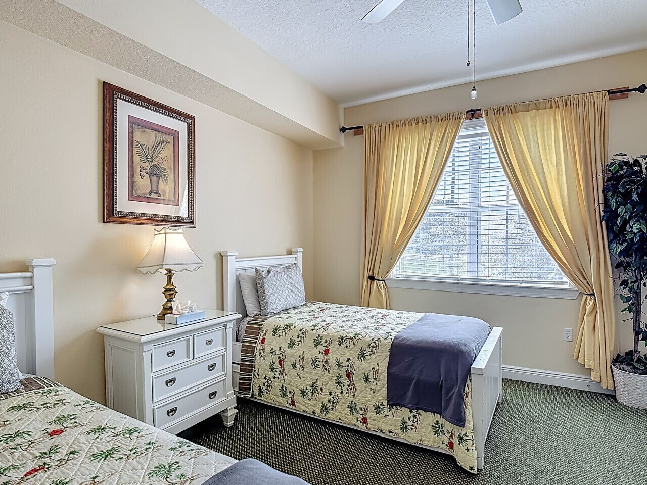 A hotel room with a bed, bedside table, lamp, and a window with curtains.