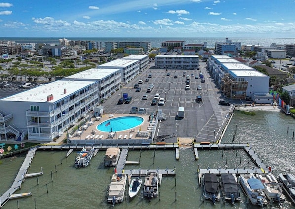 A marina with boats docked, a swimming pool, and a parking lot.