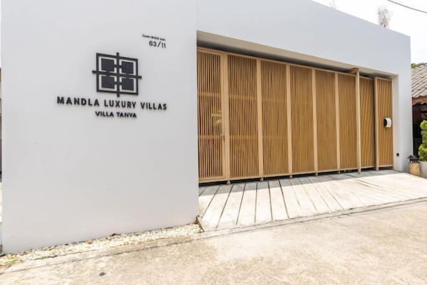 A modern building with a large sliding wooden door, a white facade, and the text 'MANDLA LUXURY VILLAS VILLA TANYA'.