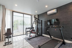 A home gym with a treadmill, weight bench, and dumbbells. - Mandla Villas Collection-Villa Tanya (Phuket)
