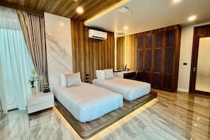 A hotel room with two beds, a desk, a mirror, a wardrobe, and a window with curtains. - Mandla Villas Collection-Villa Tanya (Phuket)