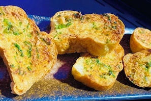 A tray of garlic bread with visible herbs. - Mandla Villas Collection-Villa Tanya (Phuket)