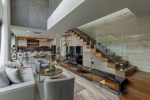 A modern living space with a staircase, a dining area, and a kitchen. - Mandla Villas Collection-Villa Tanya (Phuket)