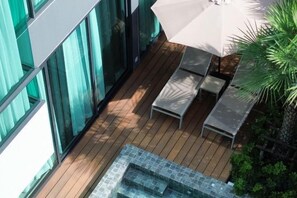 A wooden deck with a glass-enclosed hot tub, outdoor seating, and a large umbrella providing shade. - Mandla Villas Collection-Villa Tanya (Phuket)