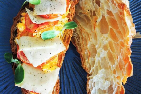 A sandwich with cheese, tomato, and greens on a blue plate. - Mandla Villas Collection-Villa Tanya (Phuket)