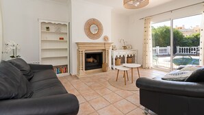 Una sala de estar con chimenea, un sofá, una mesa de comedor y vistas al exterior.