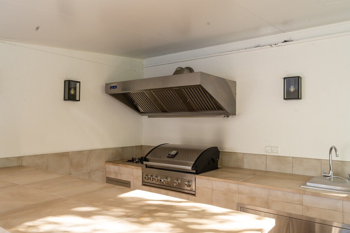 A kitchen with a built-in grill, a sink, and two wall-mounted lights.
