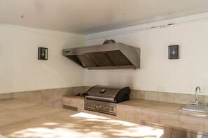 A kitchen with a built-in grill, a sink, and two wall-mounted lights. - Villa Blue Skies - Calahonda (Sitio de Calahonda)