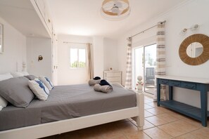 A bedroom with a bed, a bedside table, a mirror, and a view of the outdoors. - Villa Blue Skies - Calahonda (Sitio de Calahonda)