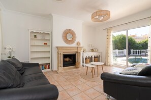 Un salon avec une cheminée, un canapé, une table basse et une vue sur l’extérieur.