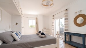 Un dormitorio con cama, mesita de noche, espejo y vistas al exterior.