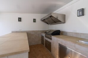 A kitchen with a built-in grill, cabinets, and a tiled backsplash. - Villa Blue Skies - Calahonda (Sitio de Calahonda)