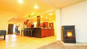 Un vaste espace de vie doté d’un plancher en bois, d’une cuisine avec un îlot central et d’un poêle à bois.
