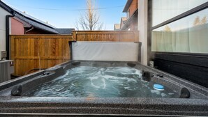 Ein Whirlpool in einem Hinterhof mit Holzzaun und einem Gebäude im Hintergrund.