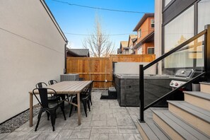 Eine Terrasse mit Tisch und Stühlen, einem Grill und einem Holzzaun.